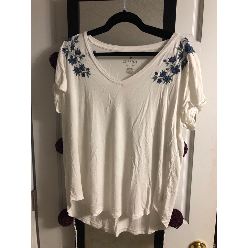 White T-shirt with blue flowers on the shoulders.